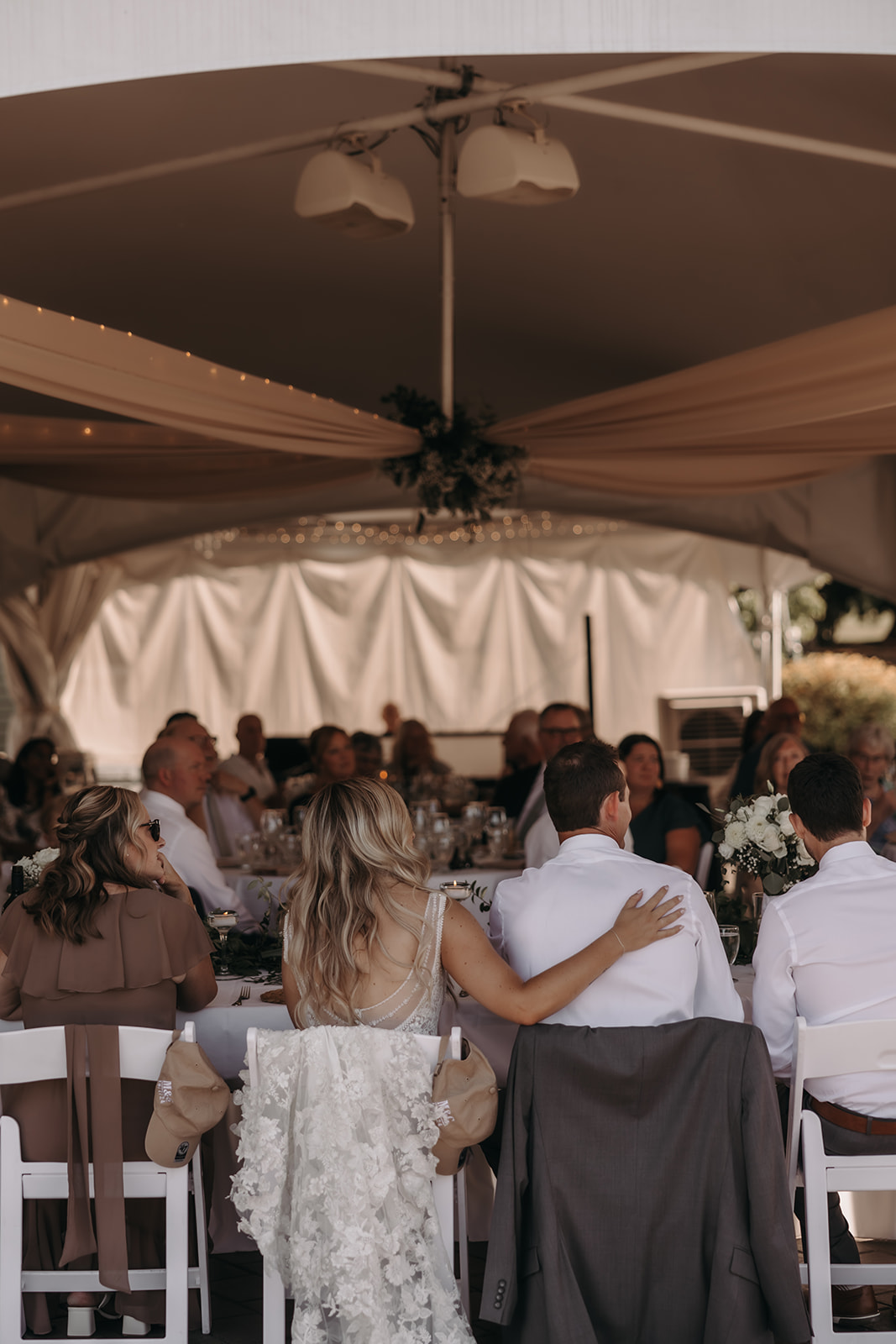 A candid moment during the reception at a Redwoods Golf Course Wedding, where guests are seated at tables and the bride rests her hand on the groom’s shoulder while gazing at the people around them.