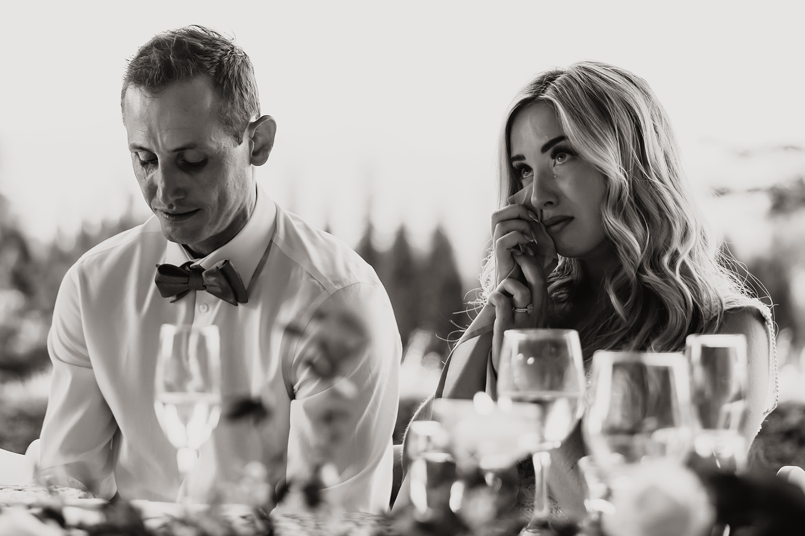 The bride and groom at their Redwoods Golf Course wedding, wiping away tears during a heartfelt moment at the reception, captured in a candid and emotional black-and-white photo.