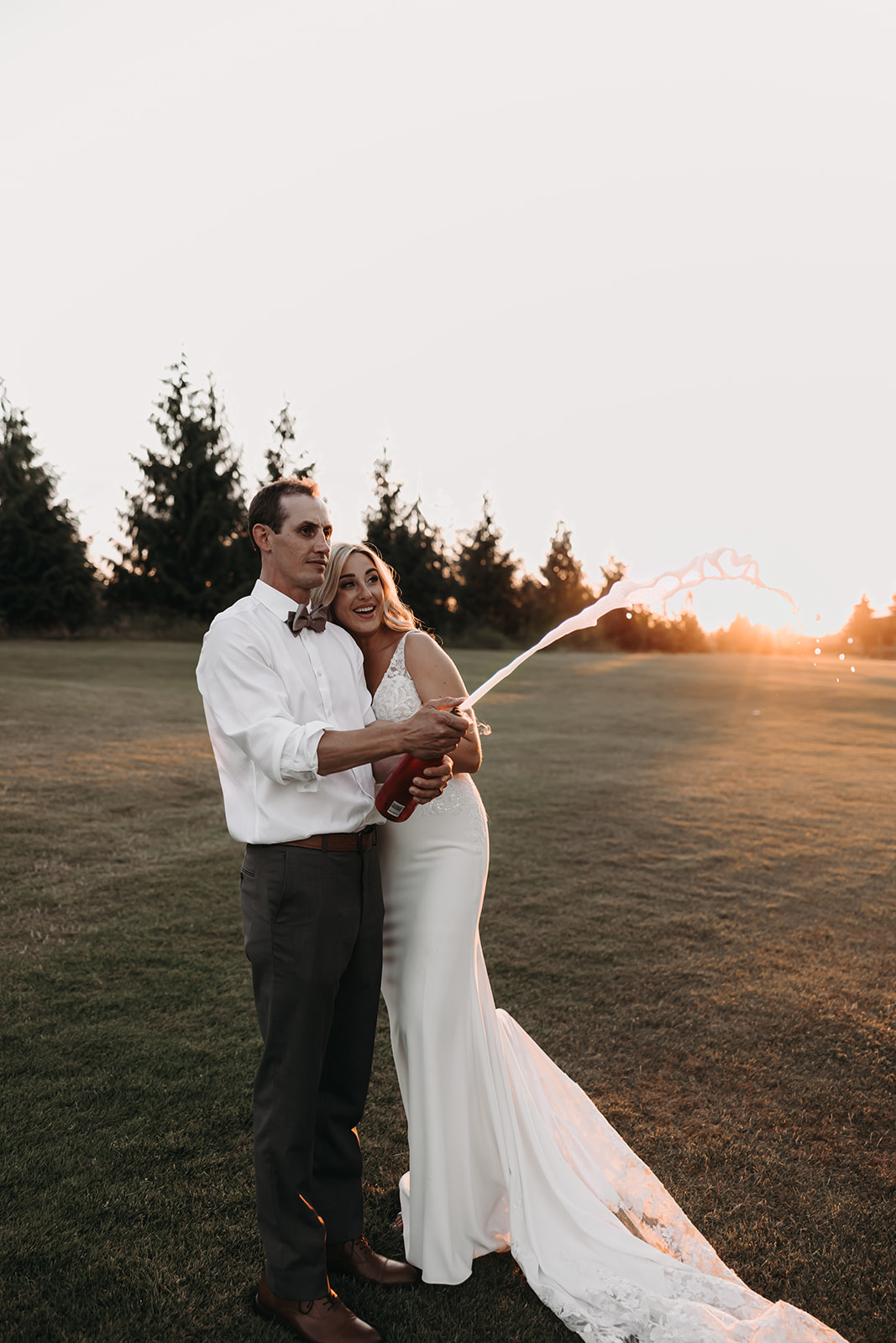 A sunset portrait of a couple at their Redwoods Golf Course wedding, popping champagne