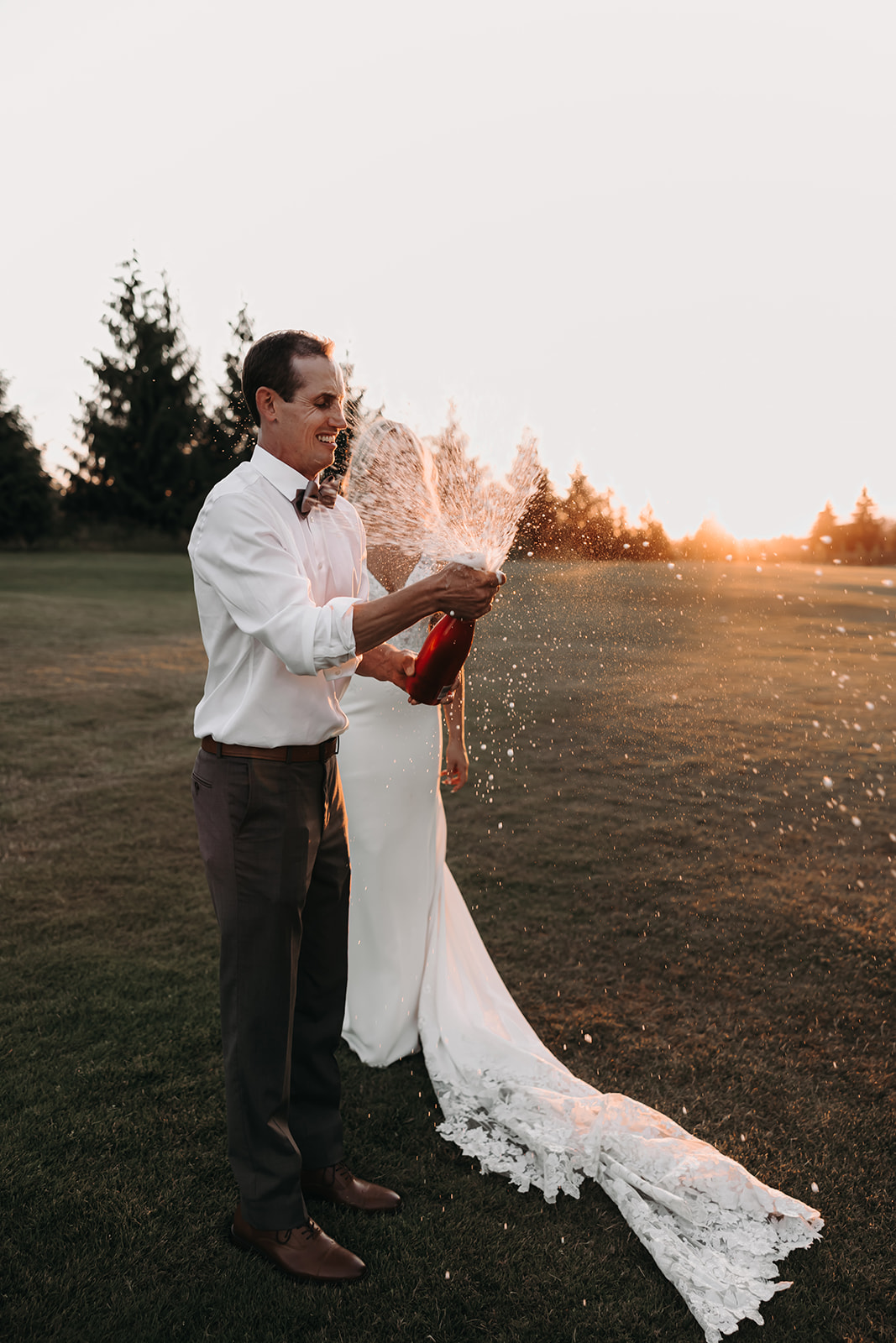 A sunset portrait of a couple at their Redwoods Golf Course wedding, popping champagne