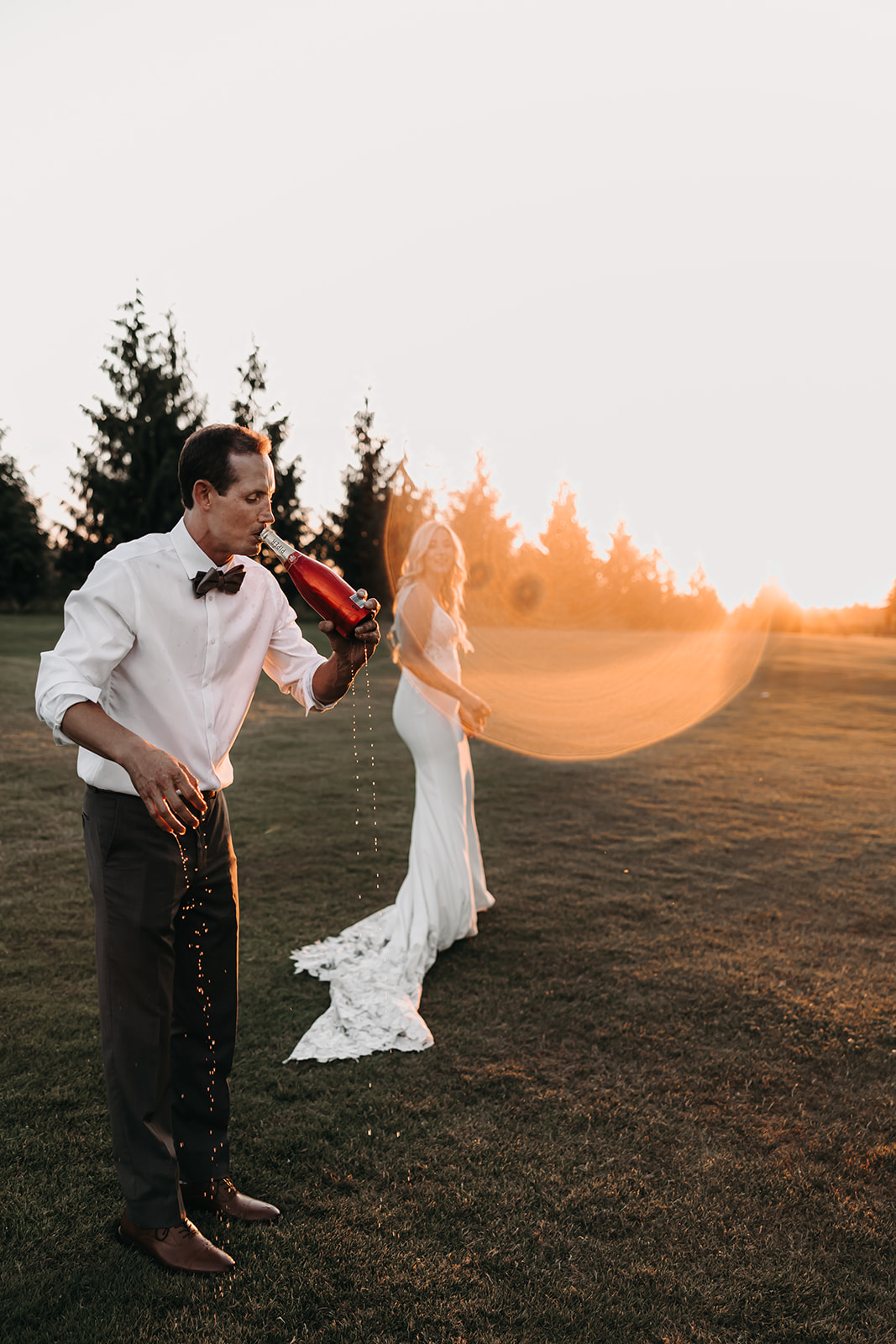 A sunset portrait of a couple at their Redwoods Golf Course wedding, popping champagne