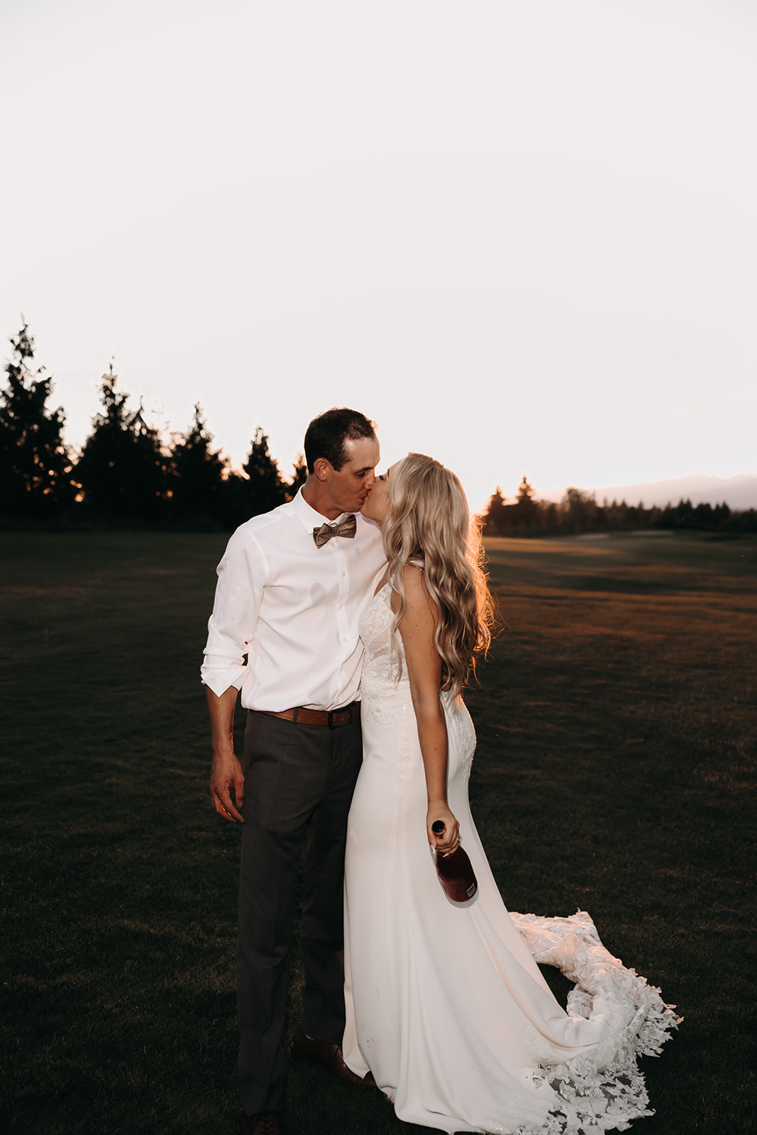 A sunset portrait of a couple at their Redwoods Golf Course wedding, popping champagne