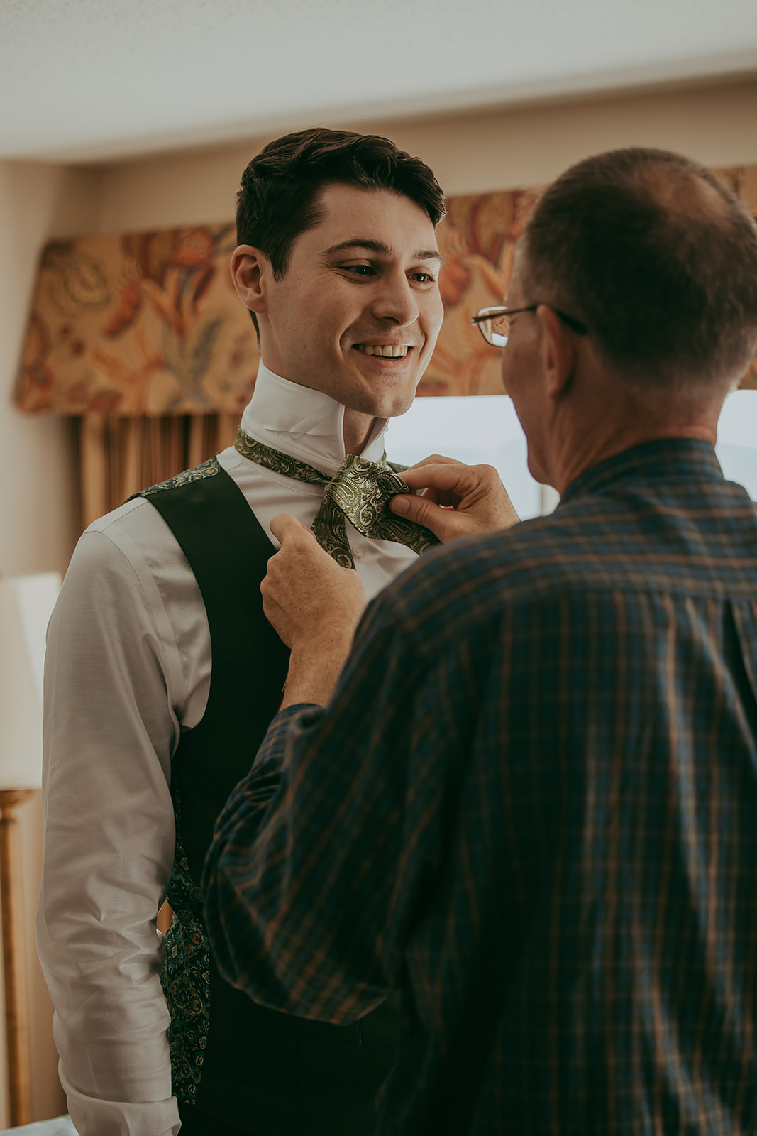 Groom getting help from his father with the bowtie before the wedding at the Lucerne Inn, a heartwarming moment from a destination wedding in Maine.