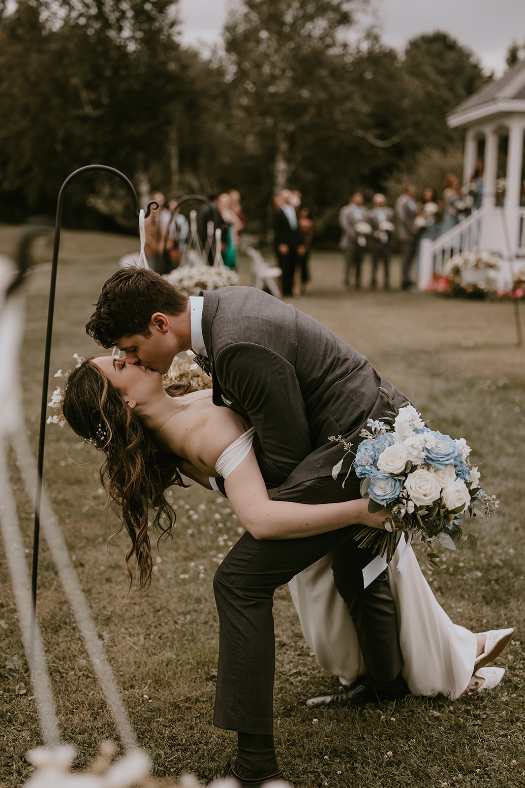 The bride and groom share a playful moment with a dip during their outdoor ceremony at Lucerne Inn in Maine, making this destination wedding feel like a dream come true.