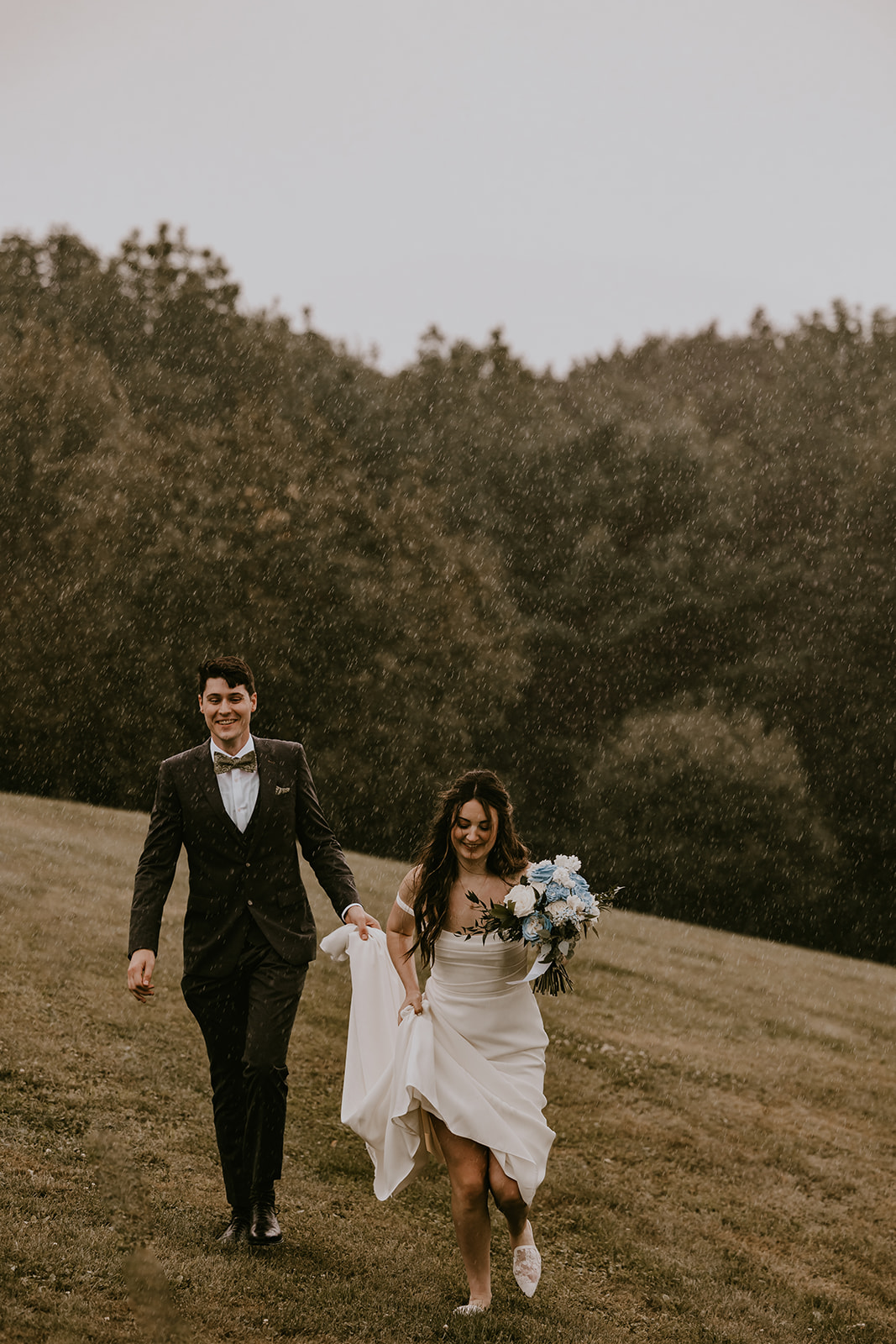 Bride and groom enjoying the rain together, walking hand in hand at the Lucerne Inn, an intimate and memorable moment from their destination wedding in Maine.