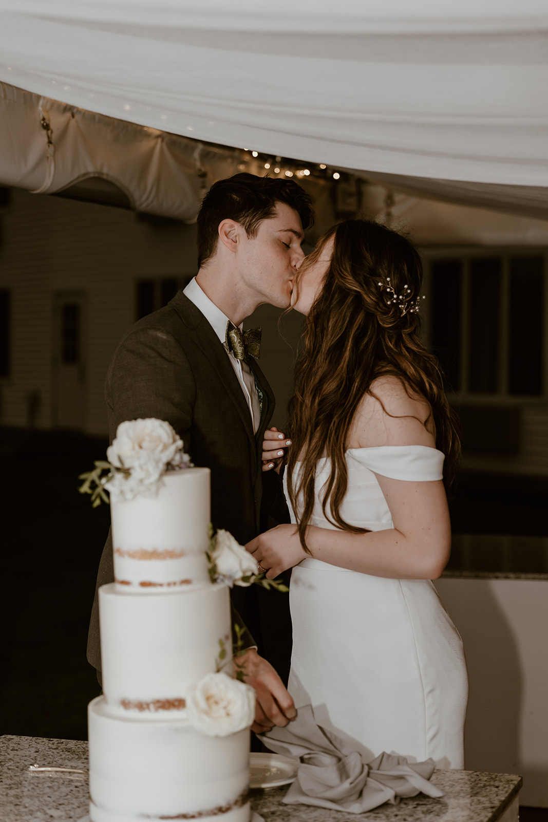 Bride and groom cutting their wedding cake kissing