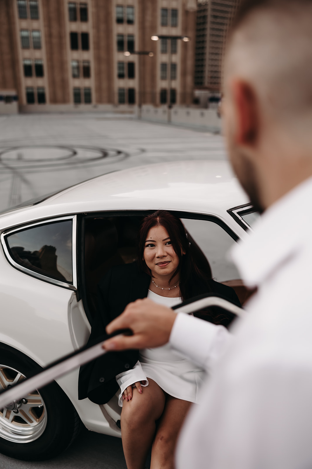 Close up shot of woman getting out of vintage car during her city engagement photoshoot on a garage rooftop