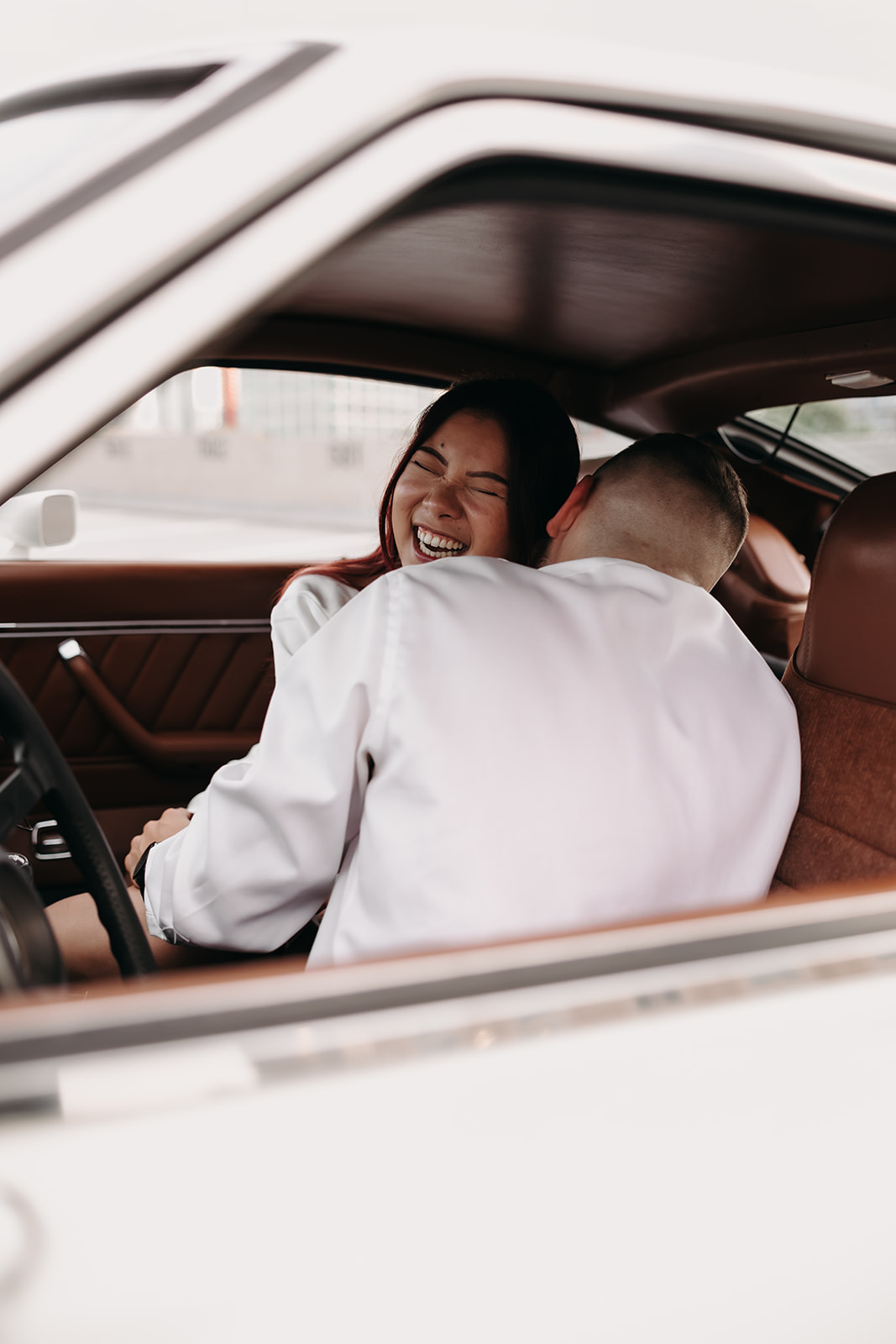 A close-up shot of the couple sharing a tender moment in their city engagement photos, as the woman wears a stylish white dress and a bow in her hair.