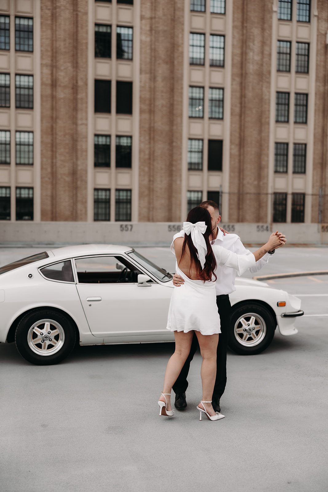 A couple dancing and laughing together for their city engagement photos on a rooftop parking lot in the heart of downtown Vancouver.