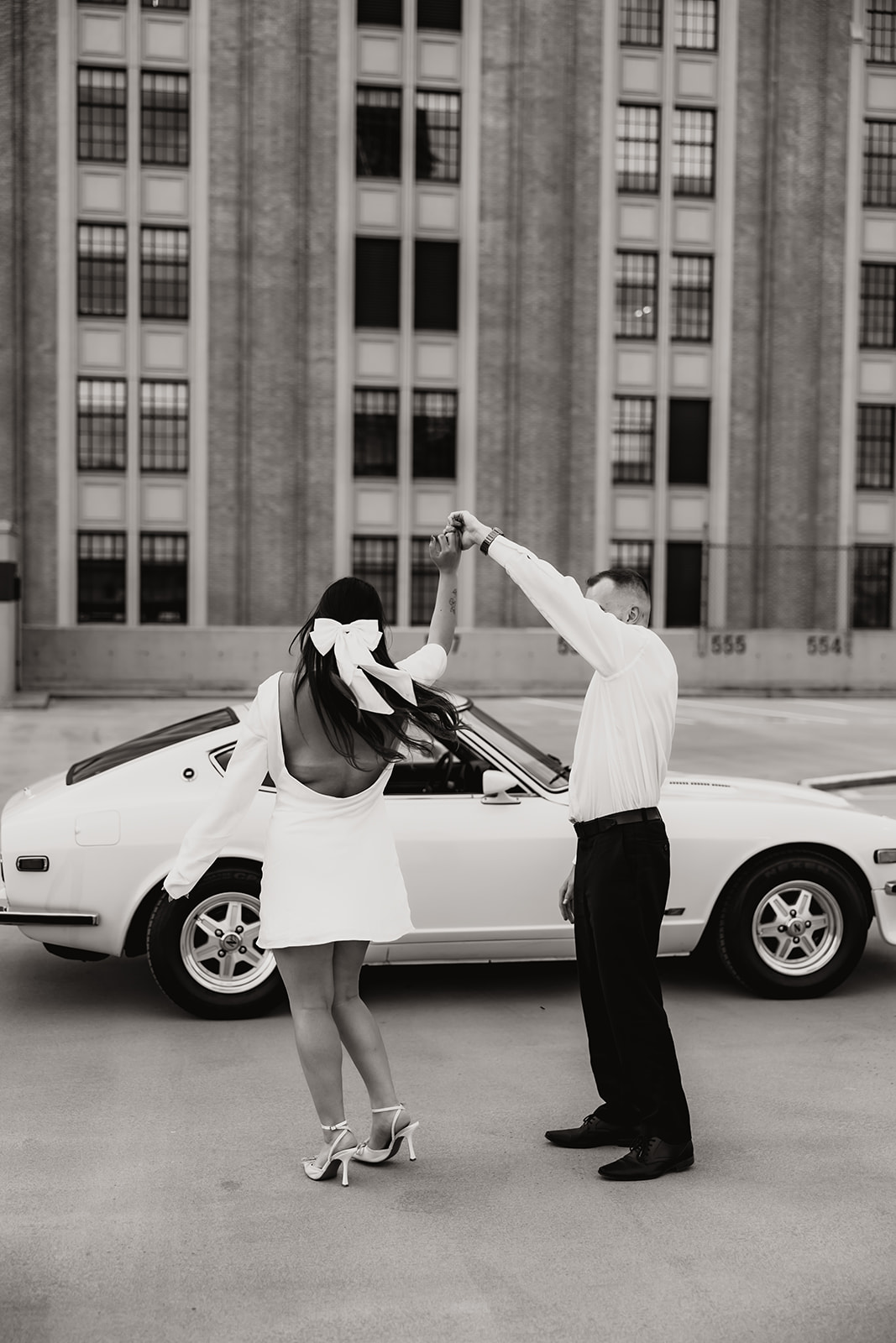 A candid moment where the couple twirls together during their city engagement photos, with the city's stunning architecture as the backdrop.