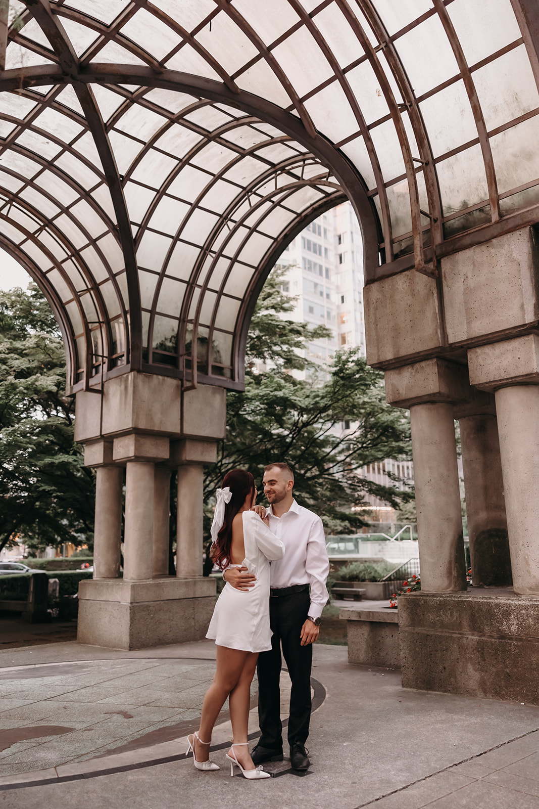 Couple dancing in a city park during their engagement photo session, sharing a playful moment together.