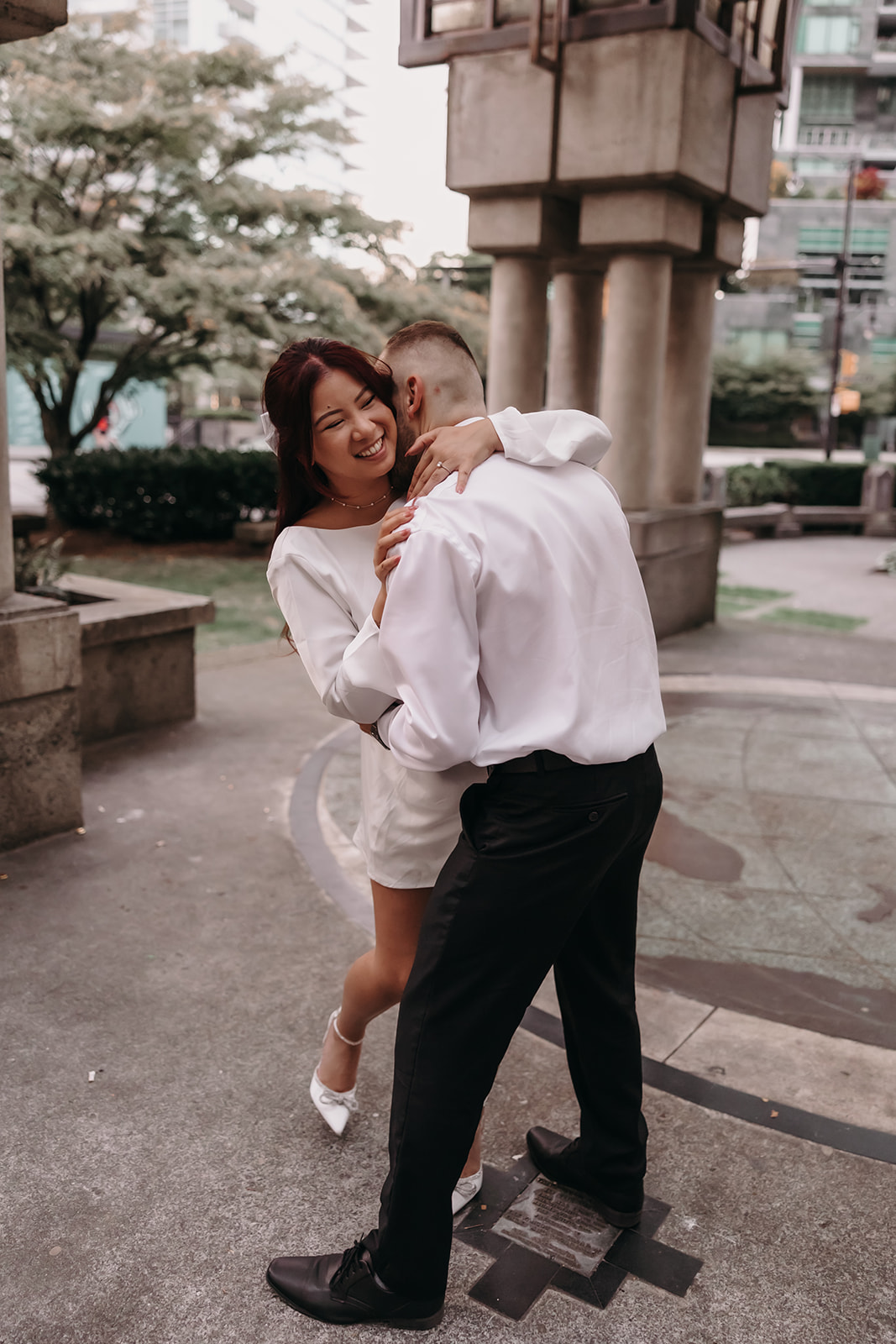 Couple dancing in a city park during their engagement photo session, sharing a playful moment together.