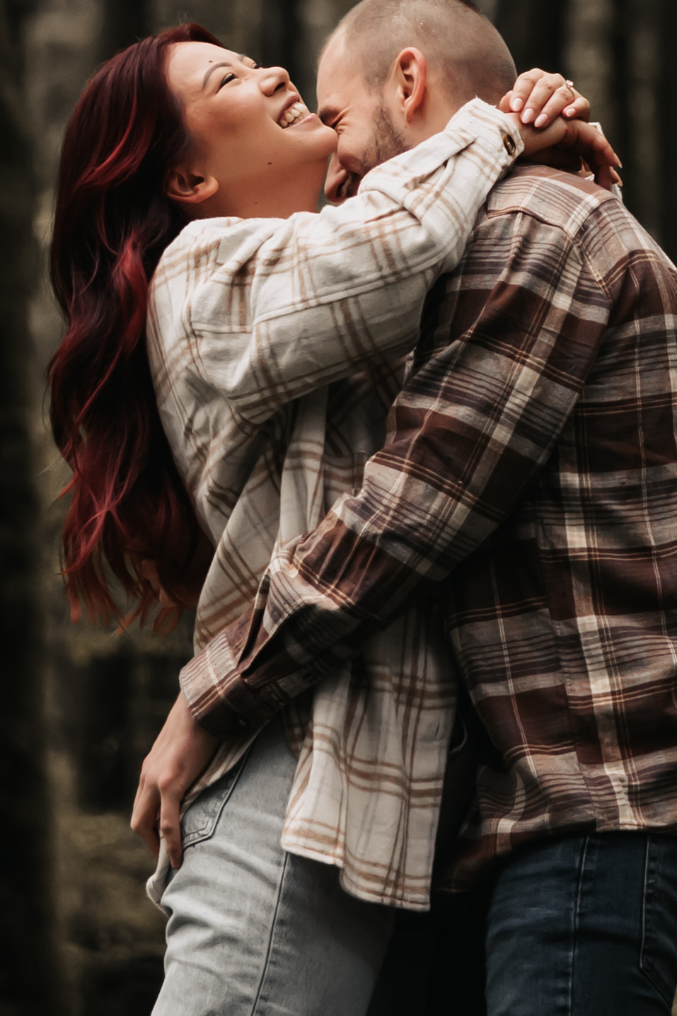 The couple shares a joyful embrace in the forest, making for an authentic and lively engagement photo