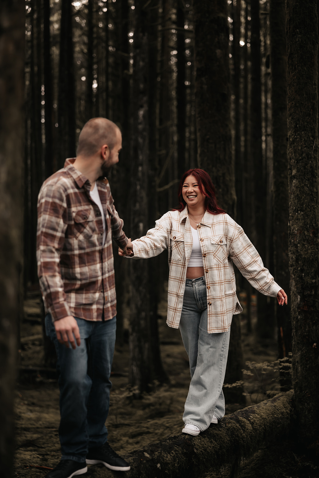 Couple walking hand-in-hand through the forest, sharing a candid and fun moment, perfect for capturing love and adventure in the wild during rainy engagement photos.