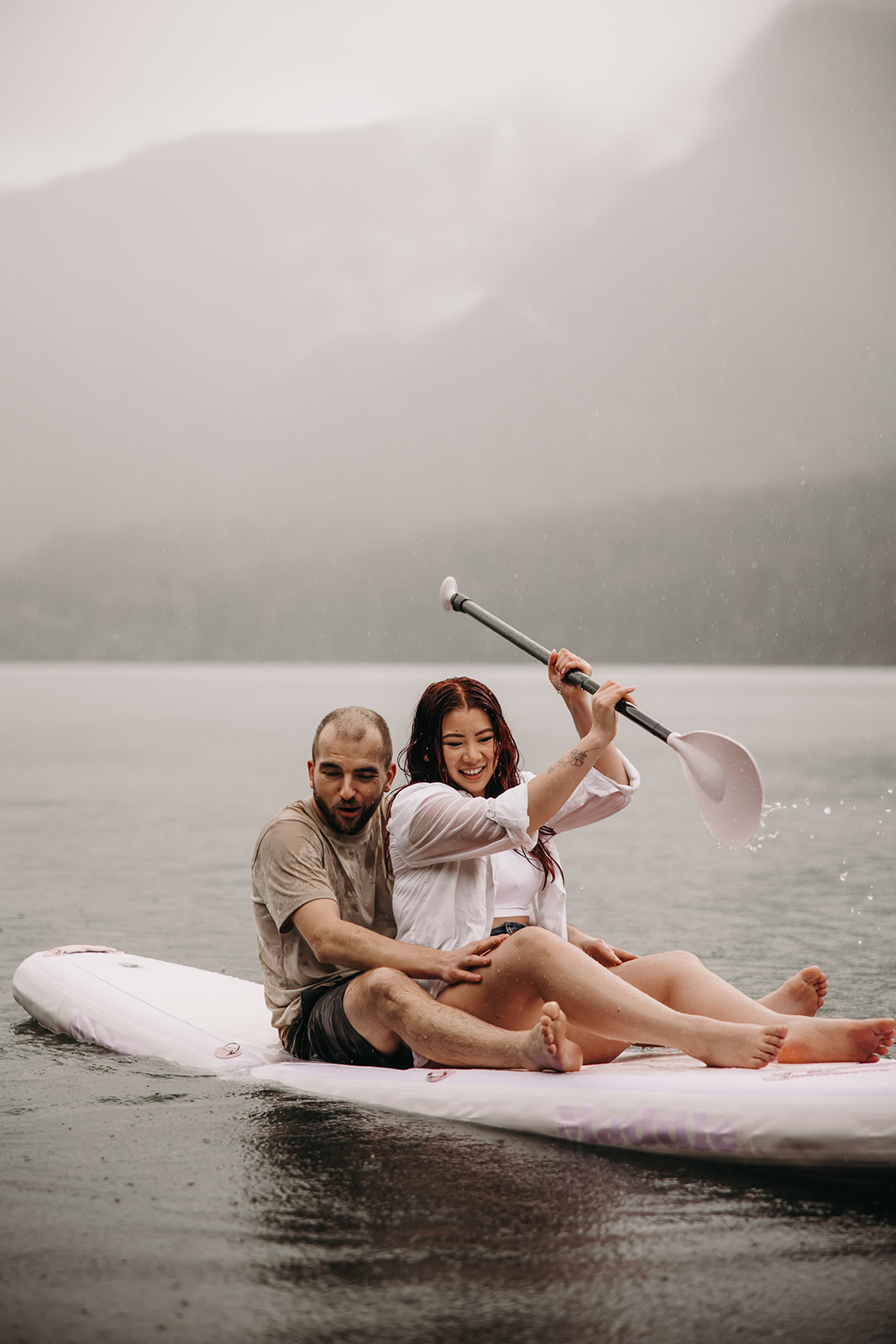 Couple laughing together while paddling during their rainy engagement photoshoot in BC.