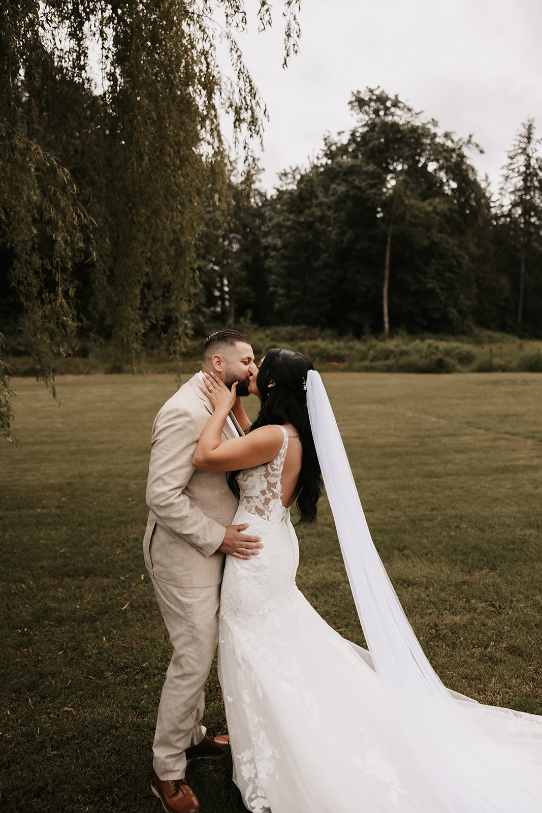 Couple shares a tender kiss, embracing their special moment during a wedding photo shoot outdoors in nature.