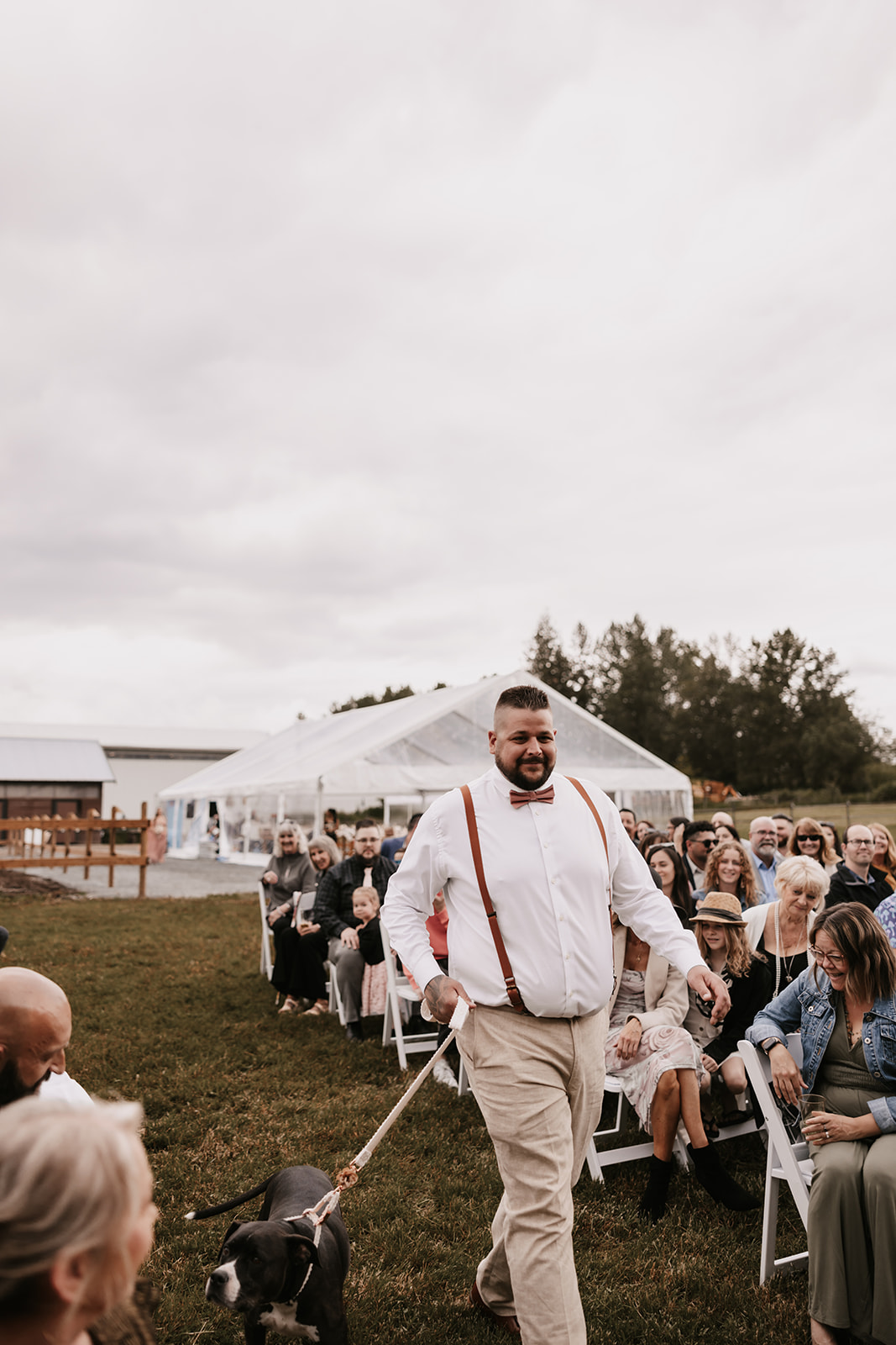 A groom walking down the aisle with a dog at the wedding, a special moment with a lighthearted and fun energy. Including your furry friend in your ceremony is a great way to make your wedding day even more enjoyable.