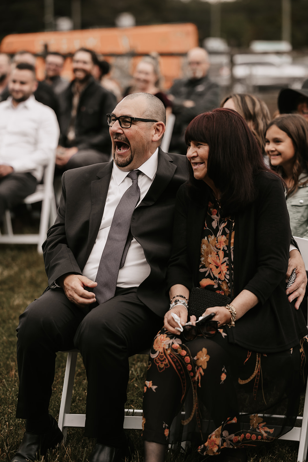 Guests at the wedding sharing a laugh while seated at the ceremony, capturing the joyous atmosphere that makes your wedding day memorable and enjoyable.