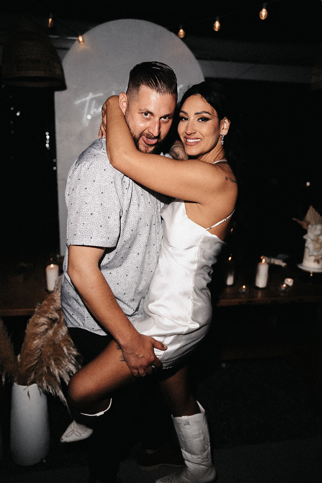 A candid image of the bride and groom embracing at their wedding reception, laughing and enjoying each other’s company in a fun, relaxed moment. This is how to enjoy your wedding day—focusing on the joy and love with your partner.