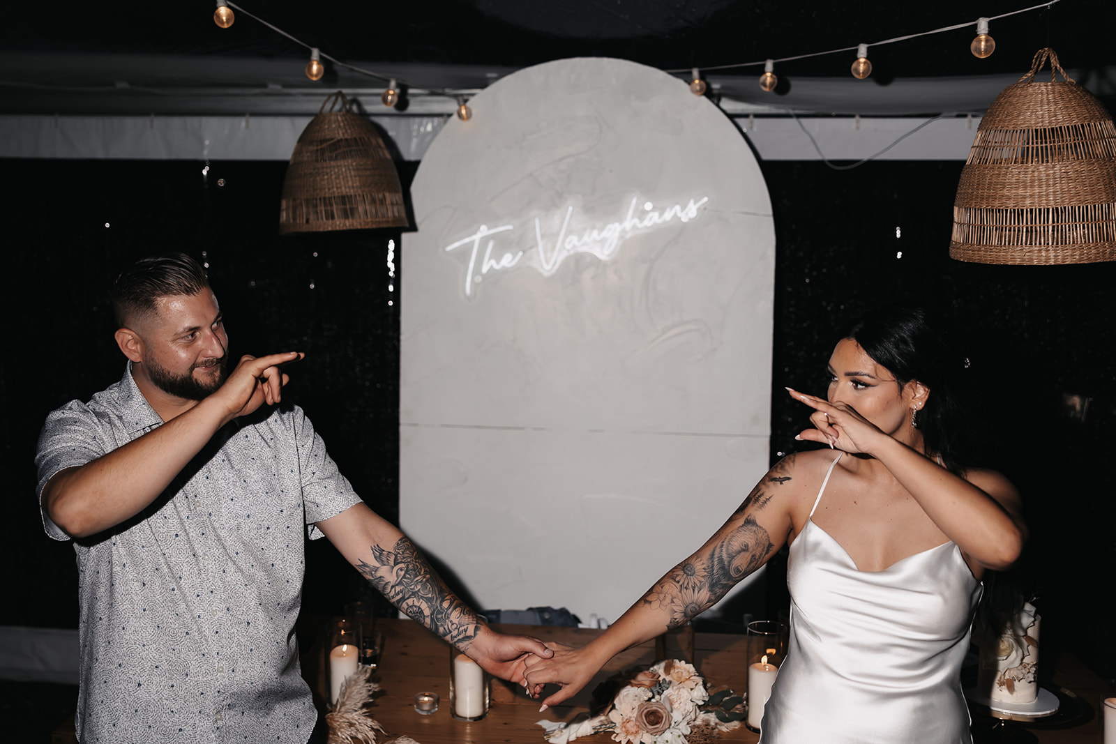 Bride and groom throwing up hang loose signs to eachother during their reception