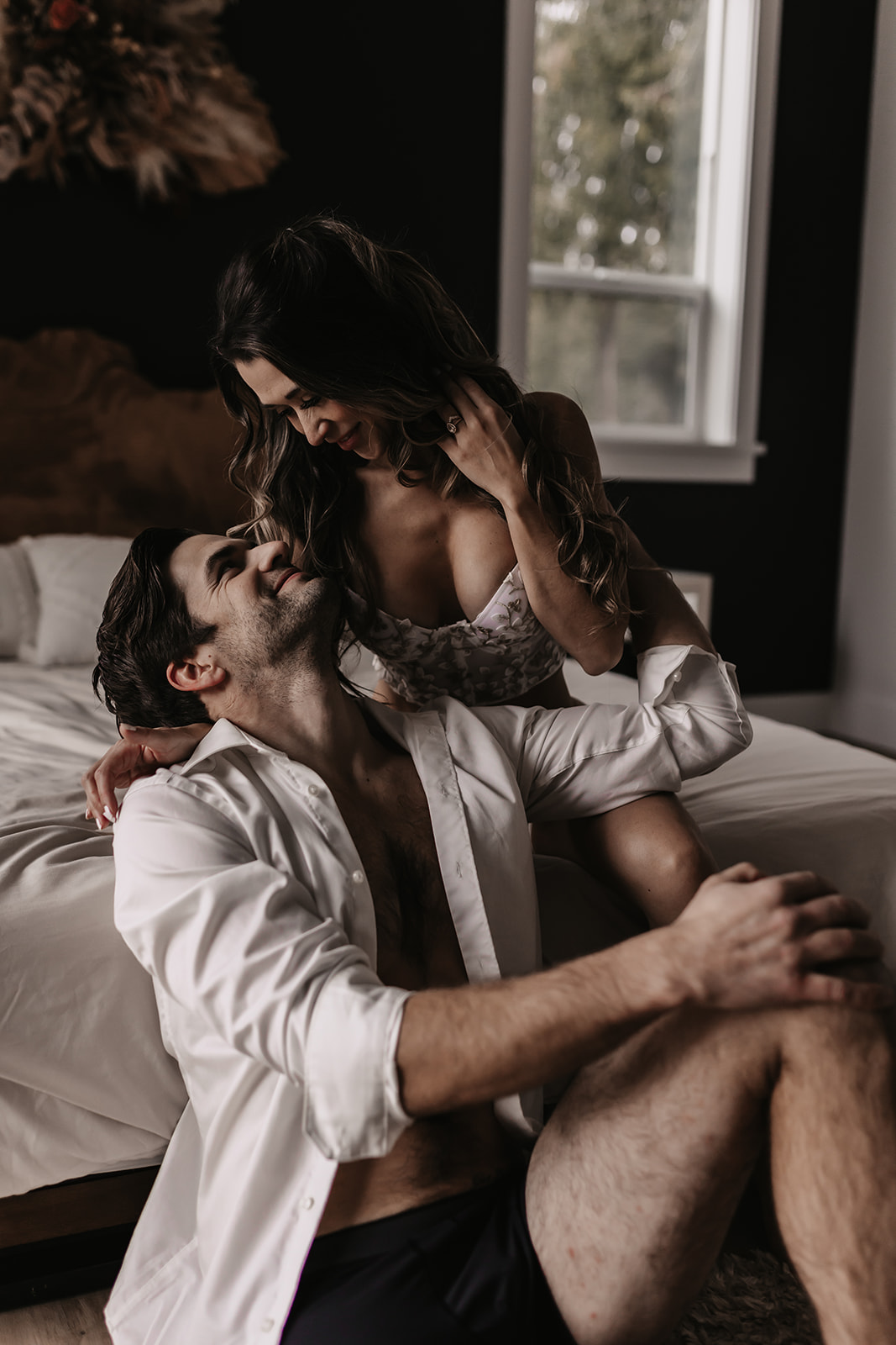 A playful and loving moment captured between a couple as they lie together in bed, perfect for fun engagement photo ideas that showcase natural affection.