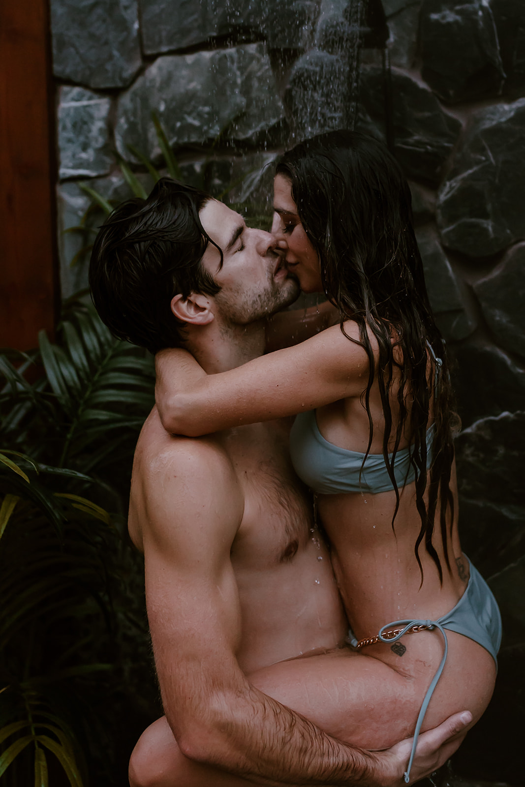 Couple playfully taking an outdoor shower together for their fun engagement photoshoot