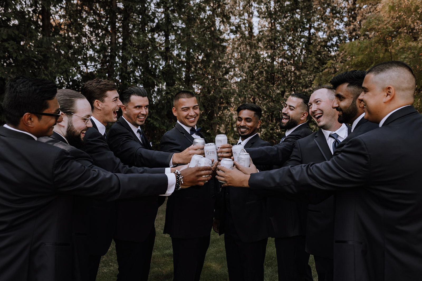 A fun moment with groomsmen toasting their beers in a cheerful and relaxed atmosphere before the wedding ceremony at a backyard wedding venue