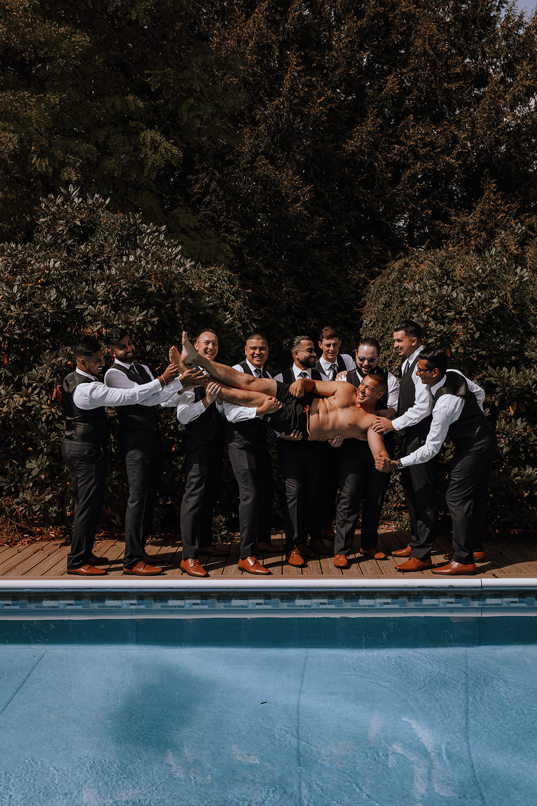 Groomsmen throwing groom into a pool