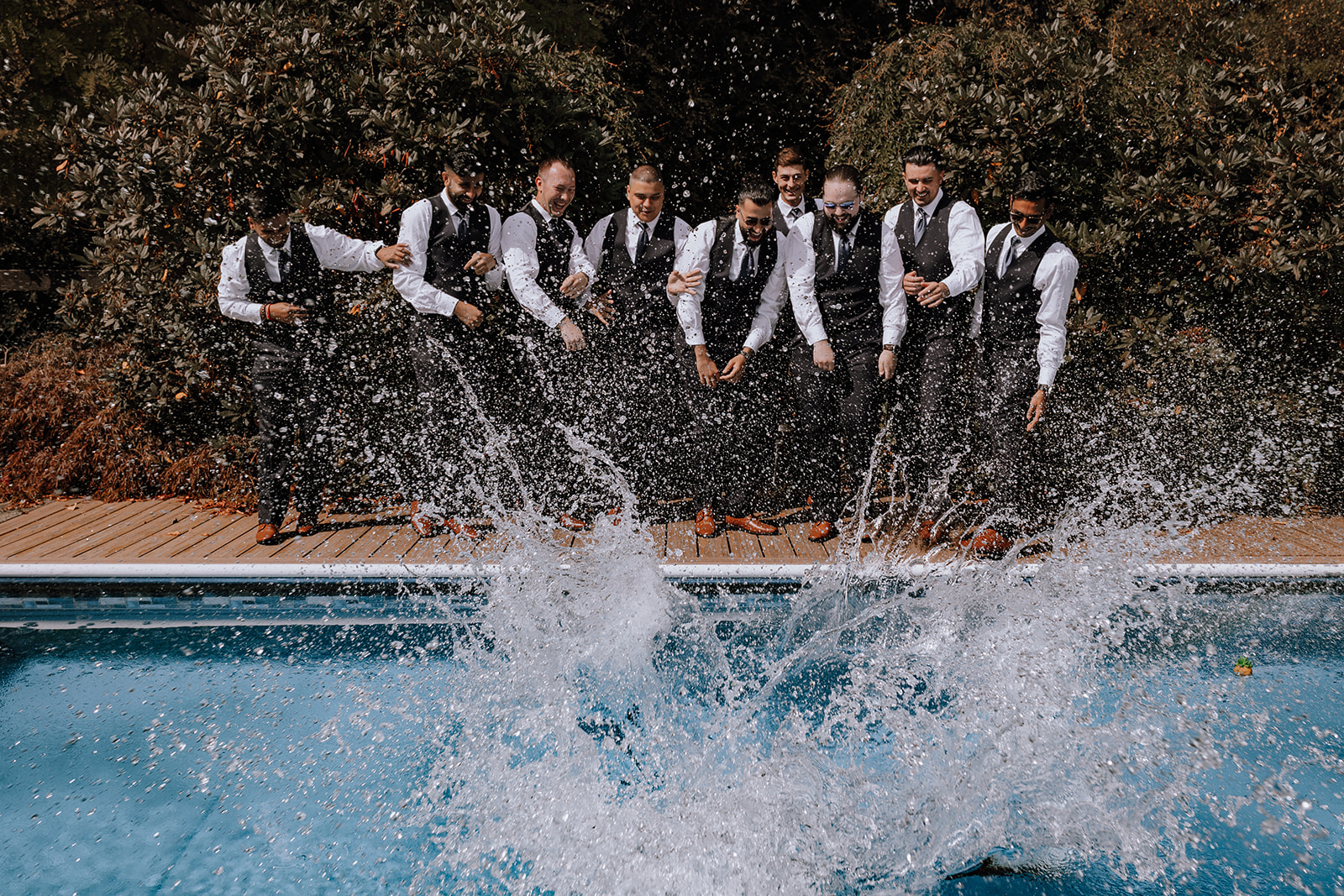 Groomsmen throwing groom into a pool