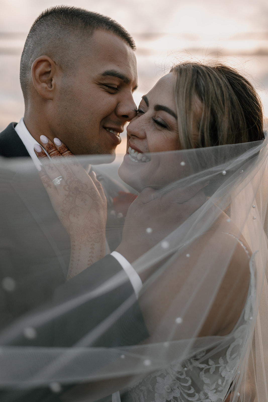 The bride and groom share a quiet moment in their backyard wedding, with the bride's beautiful lace dress flowing as they embrace against a natural backdrop.