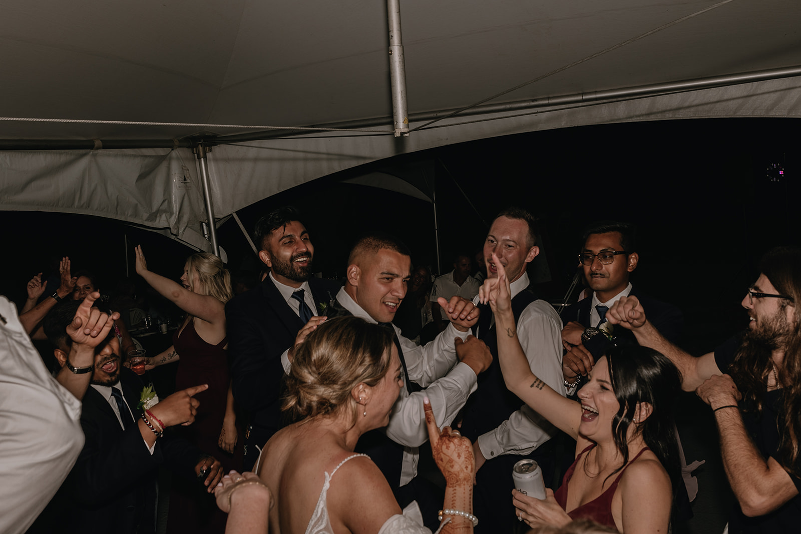 The wedding party enjoying the night at a backyard wedding reception, dancing and celebrating together, with a great mix of laughter and excitement.