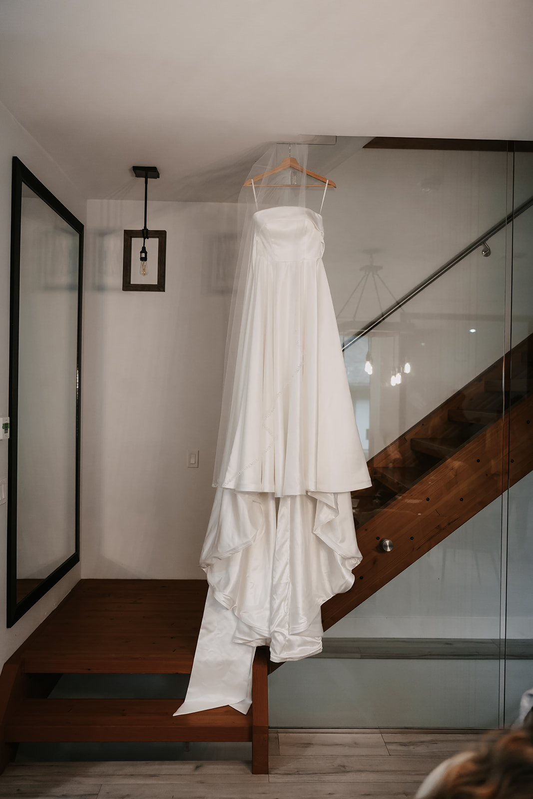 Brides white strapless wedding dress hanging from the stairway