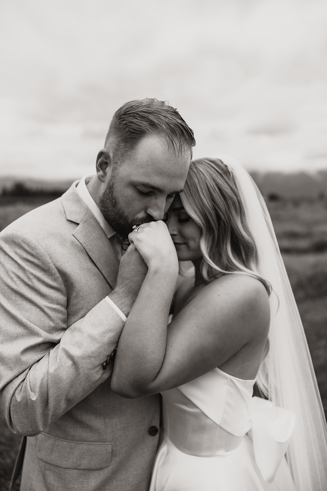 Groom kissing brides hand as they embrace eachother