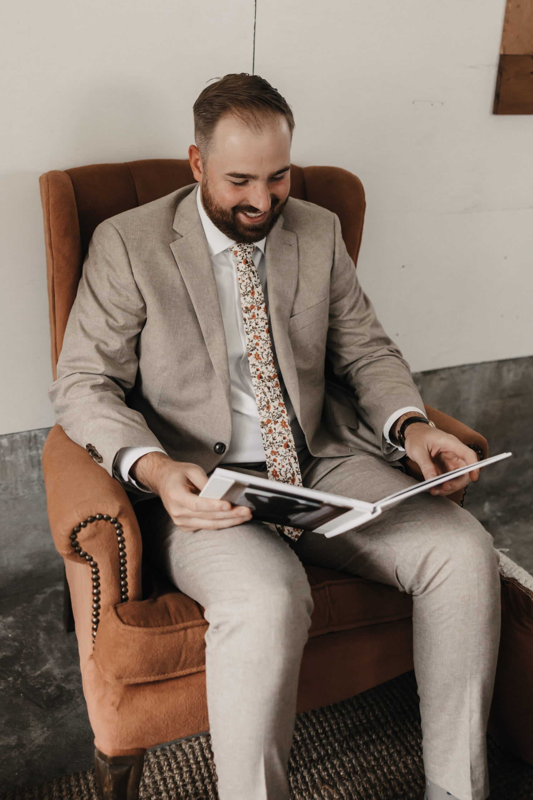 Groom reading boudoir album of bride