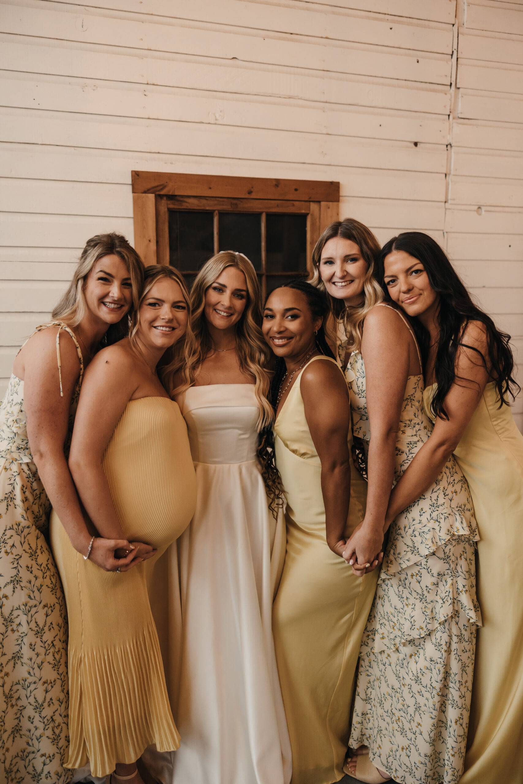 Bride and bridesmaids embracing eachother posing