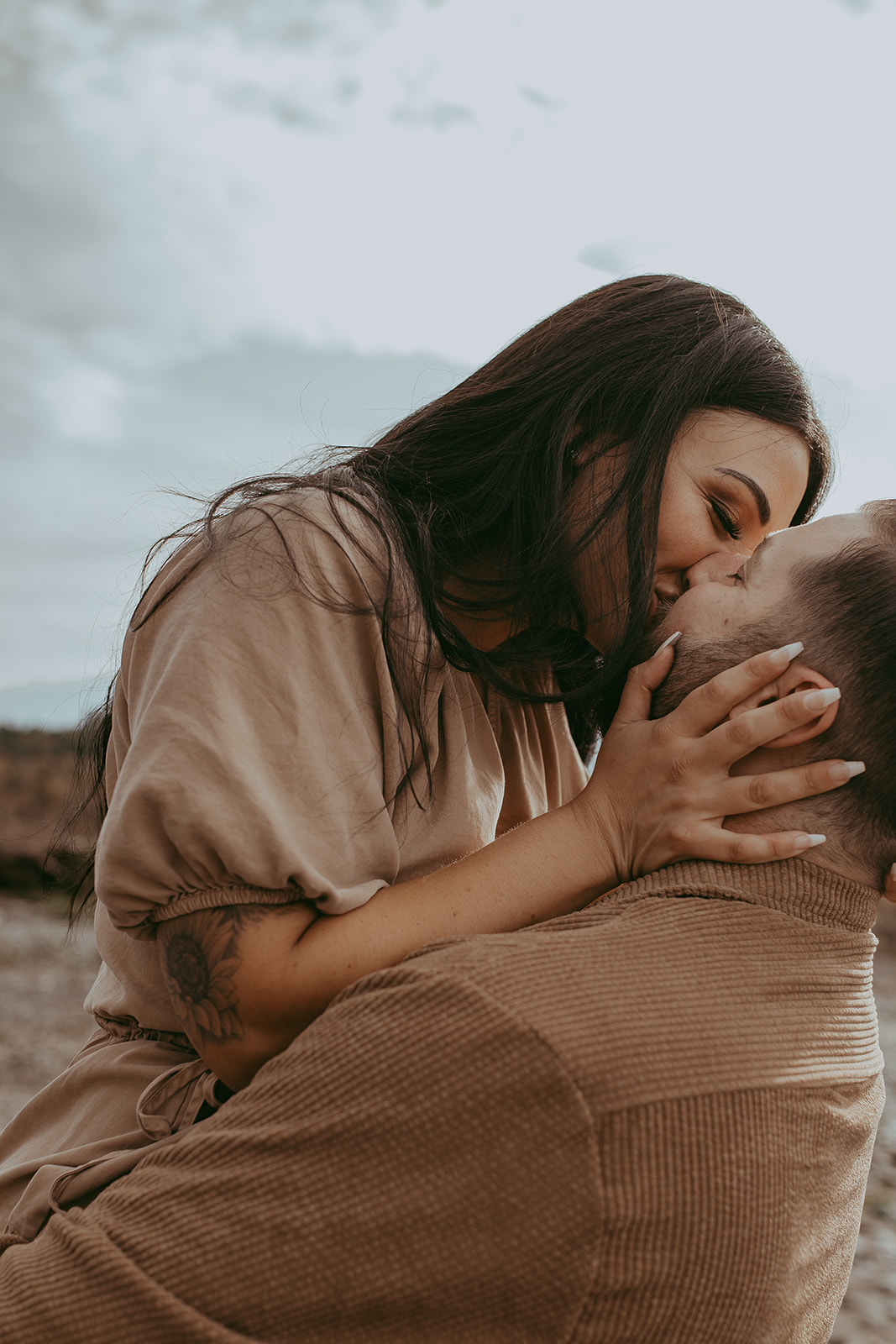 Close-up of a couple sharing an intimate kiss during their engagement session in nature, with a scenic backdrop of trees and mountains.