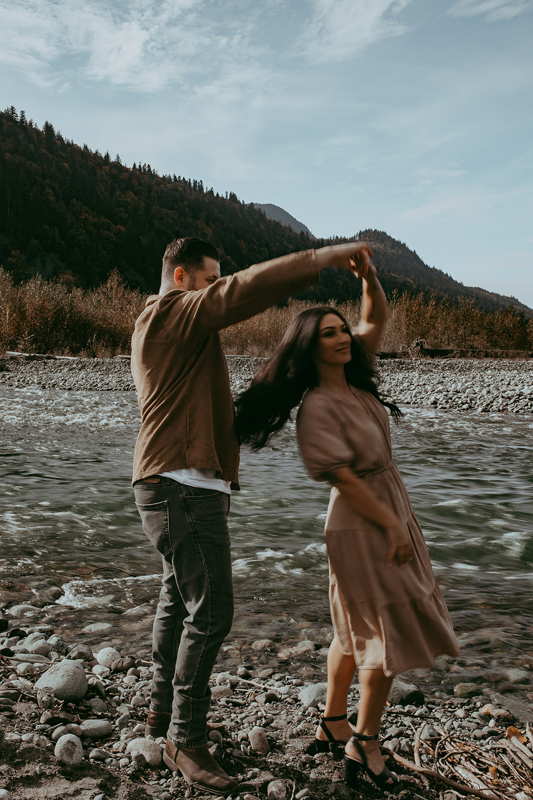 A candid moment from an engagement session as the couple twirls in the wilderness, laughing and enjoying the spontaneity of the moment.