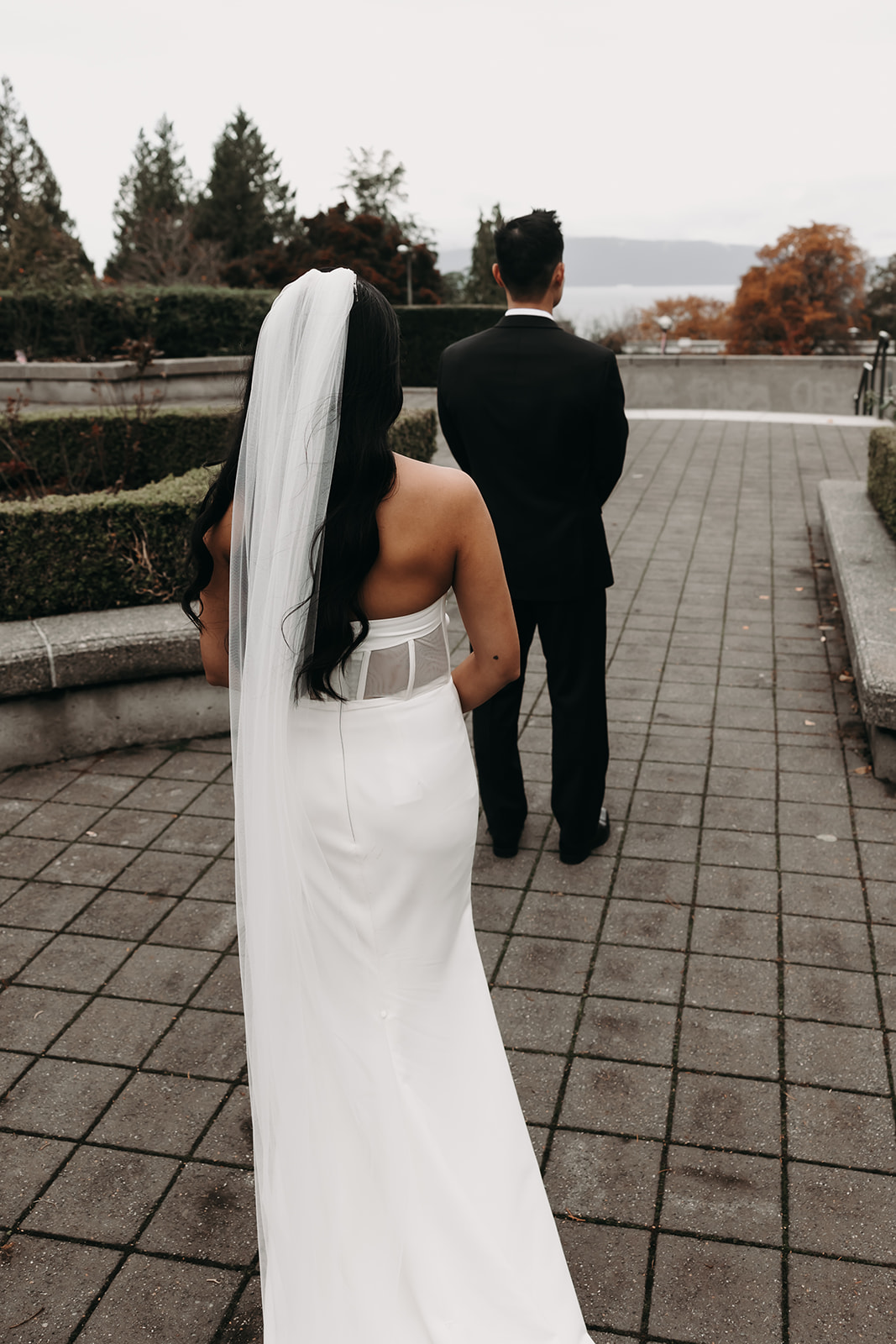 First look moment between bride and groom in Vancouver’s botanical garden. The groom’s joyful expression is captured as the bride walks toward him.