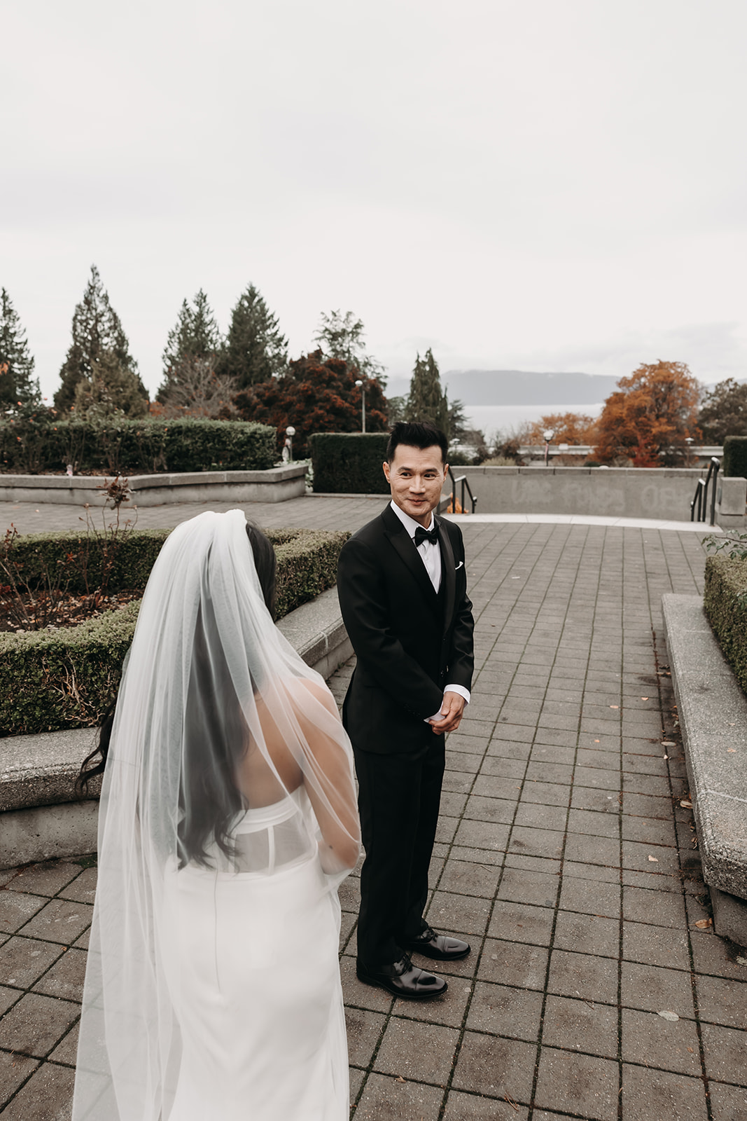 First look moment between bride and groom in Vancouver’s botanical garden. The groom’s joyful expression is captured as the bride walks toward him.