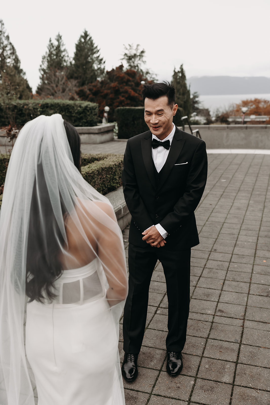 First look moment between bride and groom in Vancouver’s botanical garden. The groom’s joyful expression is captured as the bride walks toward him.