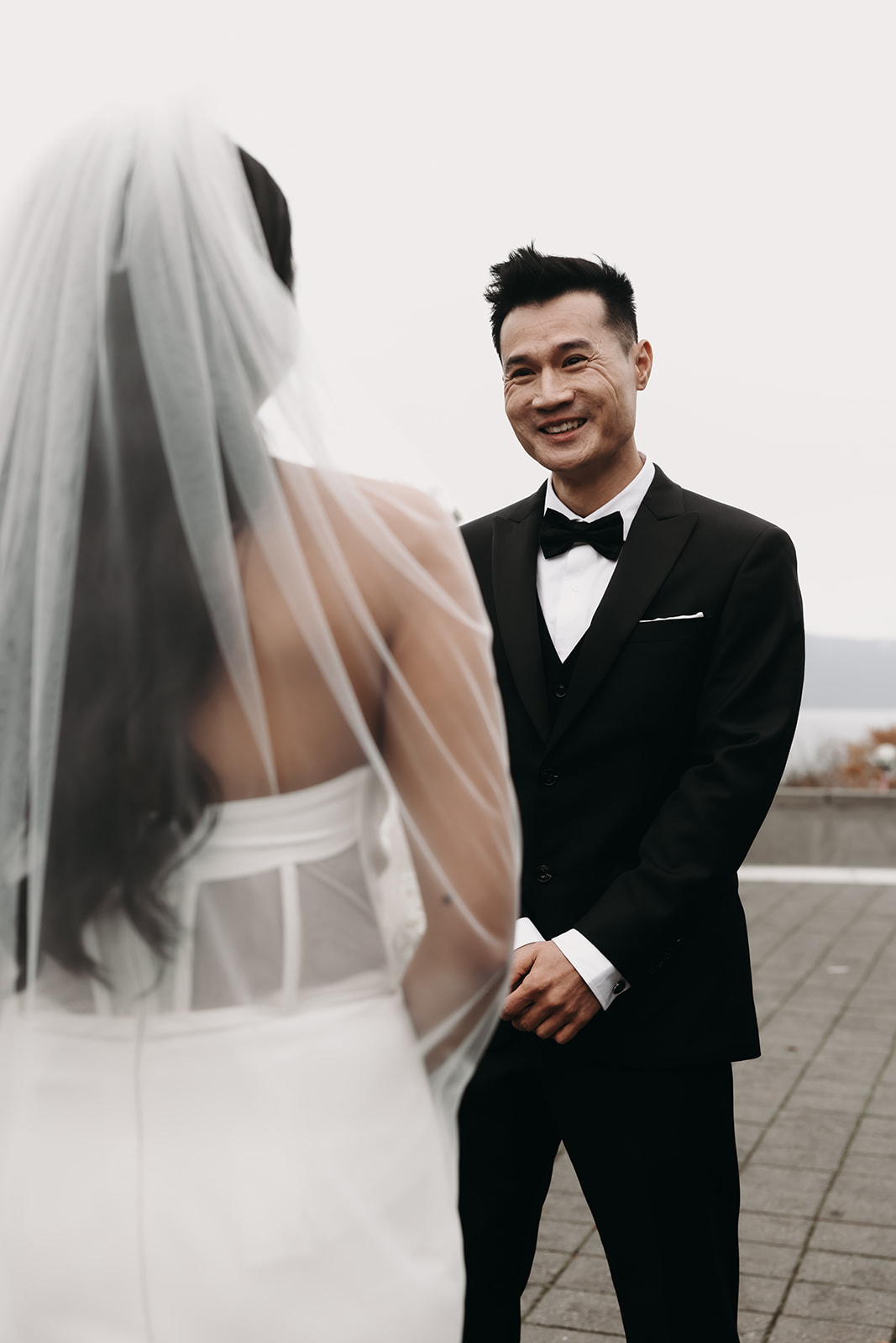 First look moment between bride and groom in Vancouver’s botanical garden. The groom’s joyful expression is captured as the bride walks toward him.