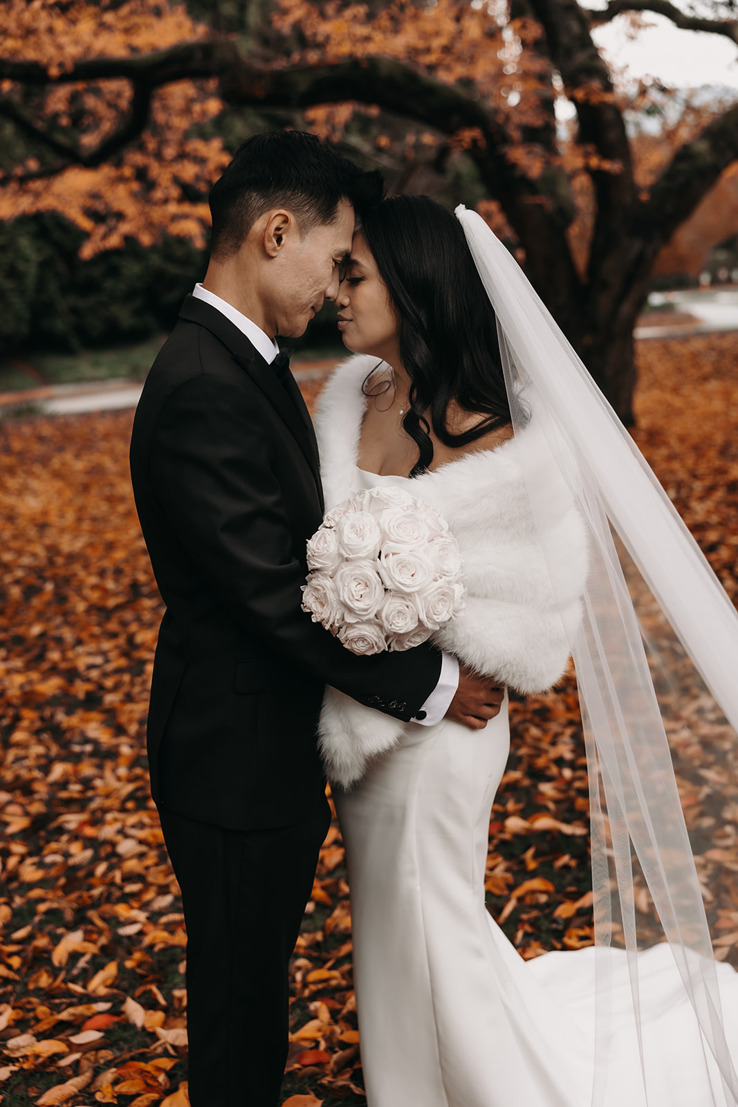 A close-up of the couple sharing an intimate moment, with their foreheads touching, amidst the autumn leaves. This candid moment adds an emotional depth to your wedding day timeline