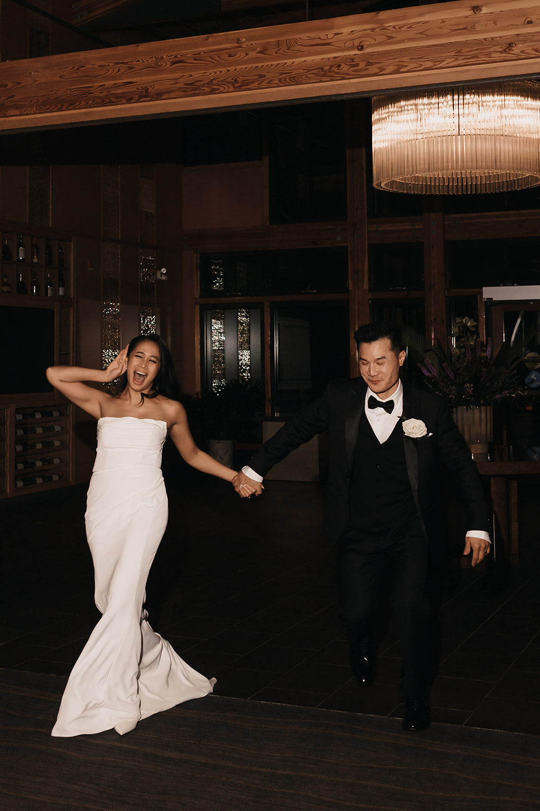 The couple happily running hand-in-hand during their wedding reception, showing off their lively personalities. Including moments like this in your wedding day timeline will ensure fun, energetic memories.