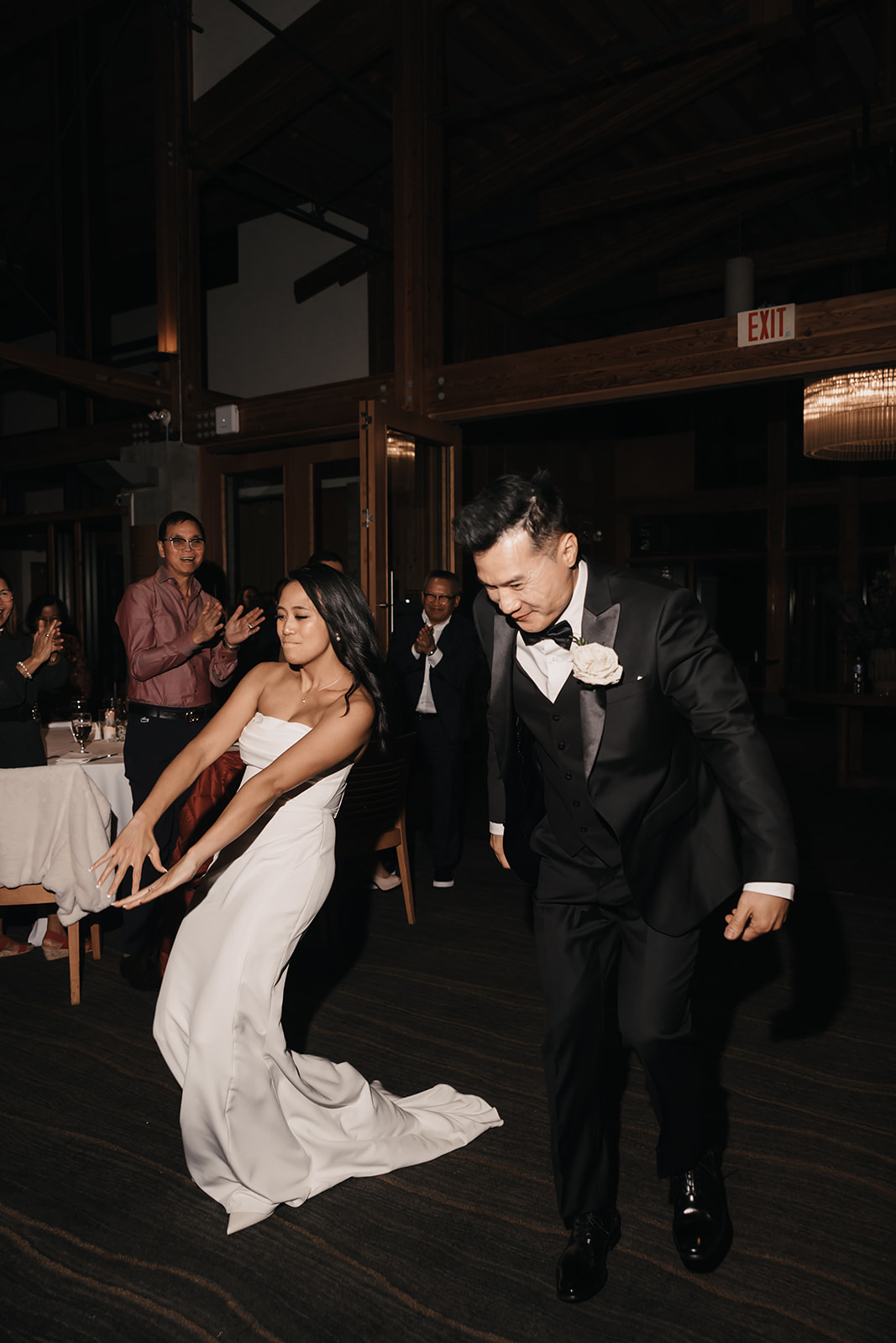 A bride and groom sharing a joyful moment, laughing and holding hands during their reception. This fun image is a great way to show the lightheartedness of your wedding day timeline.