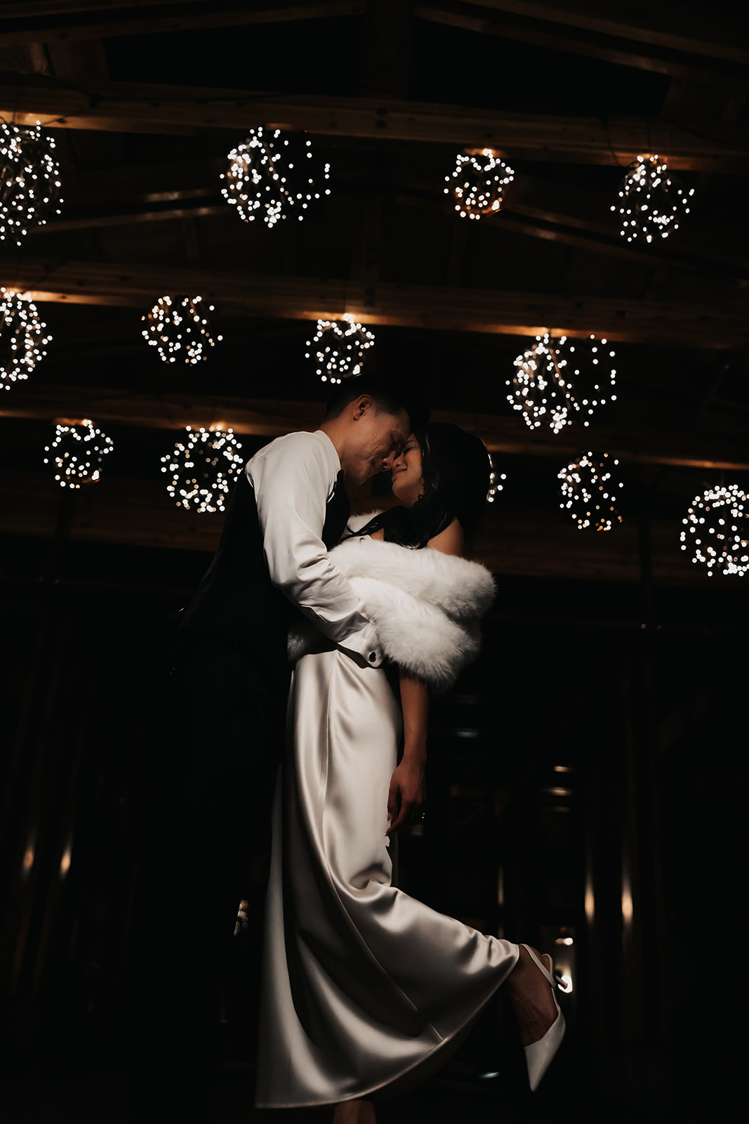 The couple embraces on the dance floor beneath the twinkling lights of the reception venue, capturing a romantic and timeless moment in the Wedding Day Timeline.